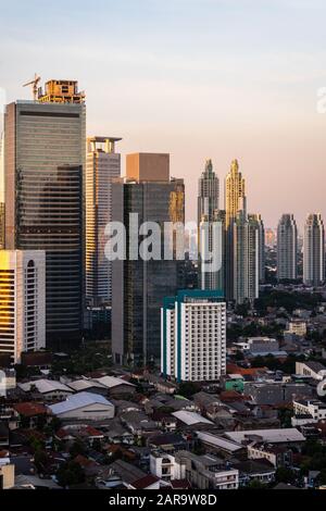 Tramonto sullo skyline di Giacarta, dove moderni condominio di lusso e torri di uffici contrastano con il basso quartiere residenziale nel centro di Jakarta, Indonesia ca Foto Stock