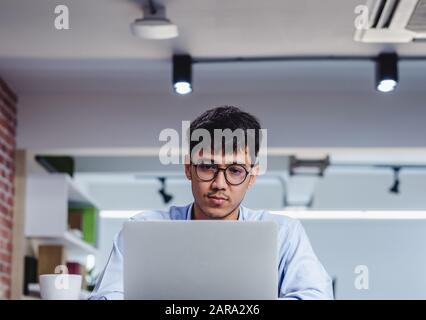 Imprenditore asiatico di Woking con il computer portatile e il foglio di lavoro sulla scrivania in ufficio.workflow digitale business online il concetto di stile di vita Foto Stock
