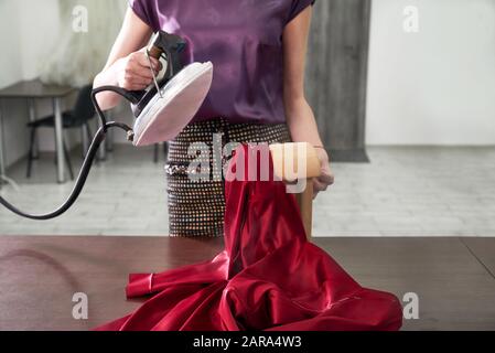 Sartoria stiratura del tessuto. Seamstress ferro vestito in un laboratorio di cucito Foto Stock