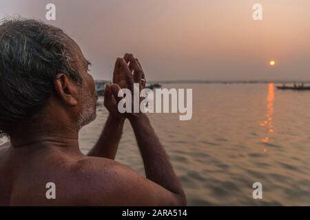 Al mattino, l'uomo che prega ai ghats del fiume santo di Gange, anche il fiume di Ganga, Varanasi anche Benares, Banaras, Uttar Pradesh, India, Asia del sud, Asia Foto Stock