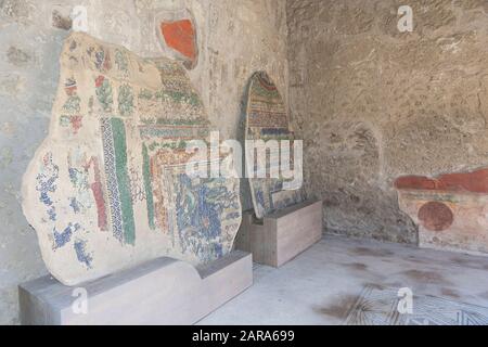 Frammenti di mura con antichi dipinti in una sala in una casa nella città romana di Pompei, Italia. Foto Stock