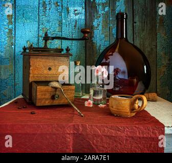 Caffè ancora vita. Una tazza di caffè caldo e aromatico, un vecchio macinacaffè manuale e cezve per preparare una bevanda. Bottiglia grande. Foto Stock