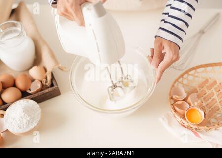 La miscelazione di colore bianco crema di uovo nella ciotola con il mixer a motore, Cottura torte Foto Stock