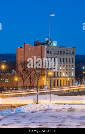 Utica, NY - 20 GEN 2020: Closeup Aerial Night View of Downtown Utica Streets and Cars Trail Lights with Commercial Travelers Life Insurance Company B Foto Stock