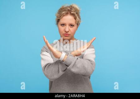 Finitura, questa è la fine. Giovane donna in felpa casual che fa x segno con le mani incrociate, gesturing stop proibito, avvertimento di divieto, linguaggio del corpo. Foto Stock