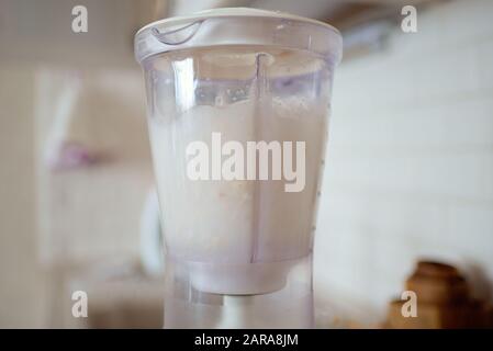 Frullatore e mandorle imbevuto di acqua. Facendo sano latte vegano. Foto Stock