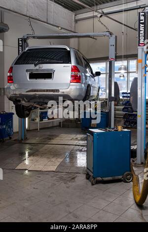 Novosibirsk, Russia - 08.01.2018: Una vettura usata in argento Acura MDX sollevata su un ascensore per riparare il telaio e il motore in un negozio di riparazione di veicoli. S. Auto Foto Stock