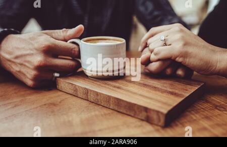 Primo piano di coppia amorevole che tiene le mani presso la caffetteria. Uomo che tiene la mano di sua moglie mentre ha caffè in un caffè Foto Stock