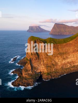 Drone aereo che vola sopra il faro di Kallur sulle verdi colline dell'isola di Kalsoy, le isole di Faroe, la Danimarca. Fotografia di paesaggio Foto Stock