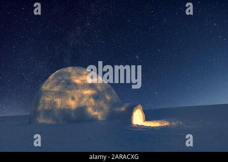 Scena invernale con snowy igloo e la via lattea nel cielo notturno. Fantastico paesaggio invernale incandescente da star light. Santa Casa da neve, ideale Anno nuovo e lo sfondo di Natale Foto Stock