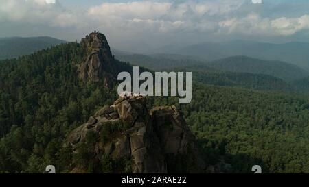 Enormi colonne di pietra dalla montagna. Arancione mattina sole. Deriva del volo del drone dell'antenna cinematografica. Bellissima natura russa Foto Stock