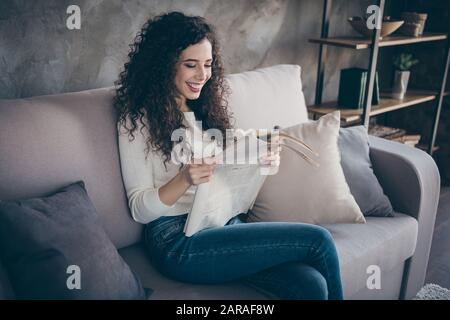 Ritratto di lei bella attraente incantevole allegra allegra ragazza con capelli ondulati seduta su divano lettura mondo notizie al moderno loft industriale Foto Stock