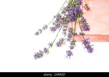 Fiori di lavanda e scatola regalo con dolci su sfondo bianco, isolato. San Valentino, bellezza, clinica medica, spa concetto. Disposizione piatta, spazio di copia. Foto Stock