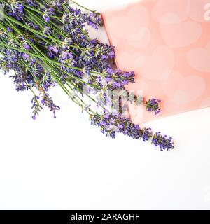 Fiori di lavanda e scatola regalo con dolci su sfondo bianco, isolato. San Valentino, bellezza, clinica medica, spa concetto. Disposizione piatta, spazio di copia. Foto Stock