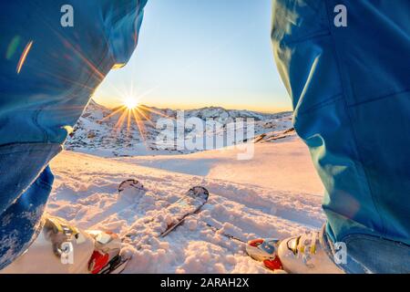 Atleta di sci in piedi di fronte al meraviglioso tramonto sulla cima della montagna - Gambe vista di giovane sciatore con luce posteriore sole - Sport e concetto di vacanza Foto Stock