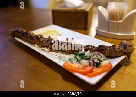 Lula kebab piatto di carne con verdure servito in ristorante su tavolo di legno. Barbecue Foto Stock