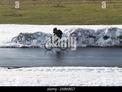 Dresda, Germania. 27th Gen 2020. Una donna ciclista fa un giro lungo il percorso ciclabile dell'Elba sulla Königsufer tra i resti di neve artificiale che è stata lasciata indietro dalla Coppa del mondo di sci. Credito: Robert Michael/Dpa-Zentralbild/Dpa/Alamy Live News Foto Stock