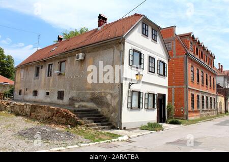 Stretta vecchia casa di famiglia di periferia allungata dilapiated con la facciata spaccata e lato frontale rinnovato vicino ai grandi blocchi di costruzione rossi di recente costruzione Foto Stock