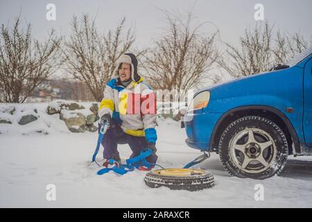 Uomo con ganci per fune di traino vicino all'auto trainata Foto Stock