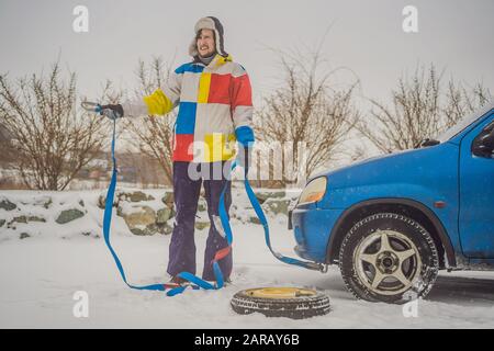 Uomo con ganci per fune di traino vicino all'auto trainata Foto Stock