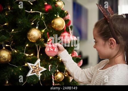 Bambino che decora l'albero di Natale Foto Stock