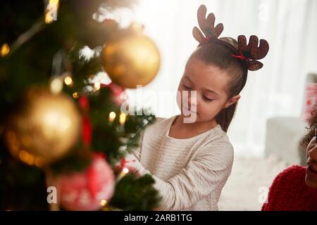 Ragazza affascinante che decora l'albero di Natale Foto Stock