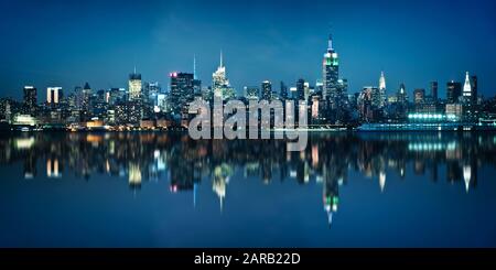 Panorama dello skyline di Manhattan visto da Jersey City durante l'ora blu. Skyline di New York di notte con riflessi. Foto Stock