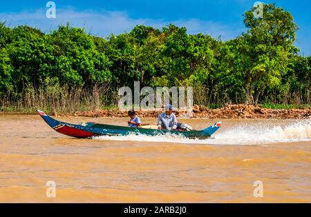 Un padre e figlio passato velocità in una barca sul lago Tonle Sap, in Cambogia. Foto Stock