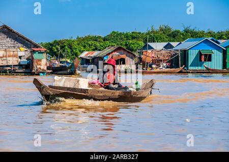 Una barca passando per le case galleggianti a Chong Kneas villaggio sul lago Tonle Sap, in Cambogia. Foto Stock