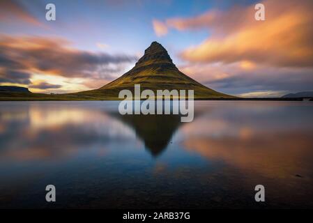 Tramonto sul monte Kirkjufell con riflessione in un vicino lago in Islanda Foto Stock