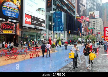 NEW YORK, Stati Uniti d'America - 10 giugno 2013: la gente visita rainy Times Square a New York. La piazza allo svincolo di Broadway e la settima avenue ha circa 39 milioni di visi Foto Stock