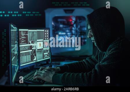 Pericoloso hacker incappucciati nel suo nascondiglio che ha un'atmosfera buia, più schermi Foto Stock
