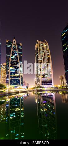 25 ottobre 2019; Indigo Tower, Jumeirah Lake Towers JLT, Dubai, Emirati Arabi Uniti; Moderne Futuristiche Torri di notte con la riflessione sull'acqua. Foto Stock