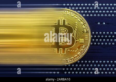 Primo piano di token di criptovaluta bitcoin dorato in movimento sulla scheda di circuito blu Foto Stock