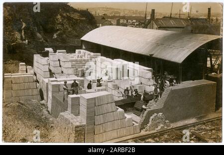 Uomini al lavoro in un'area di stoccaggio, circondata da mucchi di pietre e mattoni vicino alle banchine, da qualche parte nel Regno Unito. Foto Stock