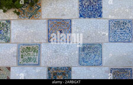 Dettagli del mosaico del trencadis della parete in ceramica e pietra del Parco Guell progettato da Antoni Gaudi, Barcellona, Spagna. Foto Stock