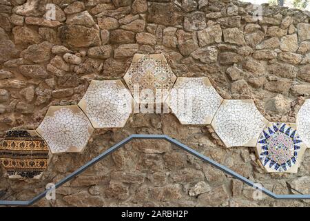 Dettagli del mosaico del trencadis della parete in ceramica e pietra del Parco Guell progettato da Antoni Gaudi, Barcellona, Spagna. Foto Stock