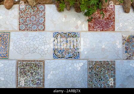 Dettagli del mosaico del trencadis della parete in ceramica e pietra del Parco Guell progettato da Antoni Gaudi, Barcellona, Spagna. Foto Stock