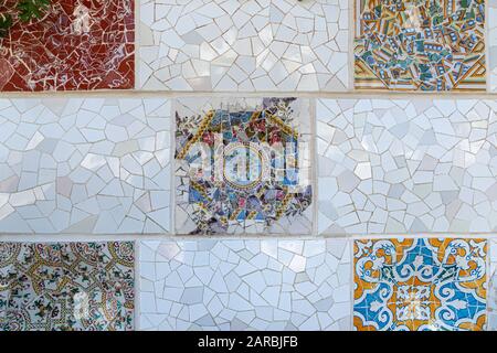 Dettagli del mosaico del trencadis della parete in ceramica e pietra del Parco Guell progettato da Antoni Gaudi, Barcellona, Spagna. Foto Stock