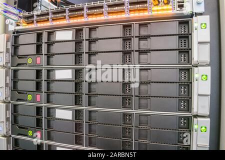 I moderni server di database con più dischi rigidi funzionano nel rack del server. L'apparecchiatura informatica si trova nel data center. Cloud farm. Foto Stock