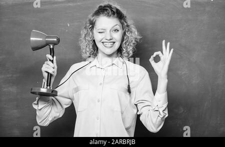 Giorno della conoscenza. Concetto di illuminismo. Creatività e ispirazione. Indicatore di direzione sul. Luce adeguata classe. Luce fino processo di studio. Insight e l'idea. Insegnante tenere la lampada da tavolo lavagna sfondo. Foto Stock