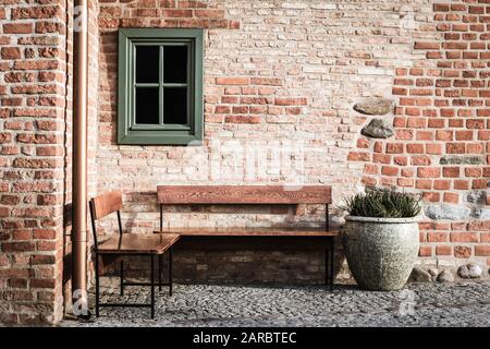 Banco vuoto in mattoni angolo muro con finestra piccola. Fotografia di stili vintage. Luogo invitante a riposo. Foto Stock