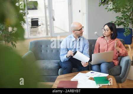 Ritratto ad alto angolo di giovane donna d'affari asiatica che parla con il manager mentre lavora su progetto di internship, copia spazio Foto Stock