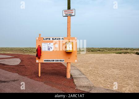 Una grande tavola gialla, Lifesaver Unit Box 24, fornisce un Torpedo Lifebuoy, istruzioni per l'uso e un telefono di emergenza in un'area di tarmac malva Foto Stock