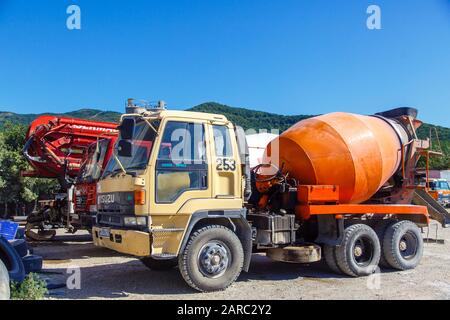 Camion di calcestruzzo sul cantiere. Le auto non sono nuove, polverose e ammaccate in luoghi. Foto Stock