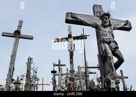 Vista a basso angolo di grande scultura di Gesù sulla croce circondata da altre croci di legno Foto Stock