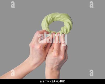 Fango appiccicoso in mano. Il fango verde nelle mani. Giocattolo preferito per un bambino. Hobby, piacevole al tocco anti-stress trainer Foto Stock