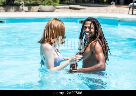 Afro-americano di uomo e donna bianca giocando in una piscina. Foto Stock