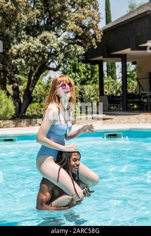 Afro-americano di uomo e donna bianca giocando in una piscina. Foto Stock