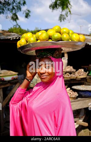 Ritratto di una donna che vende frutta con un vassoio di arance sulla sua testa. Foto Stock